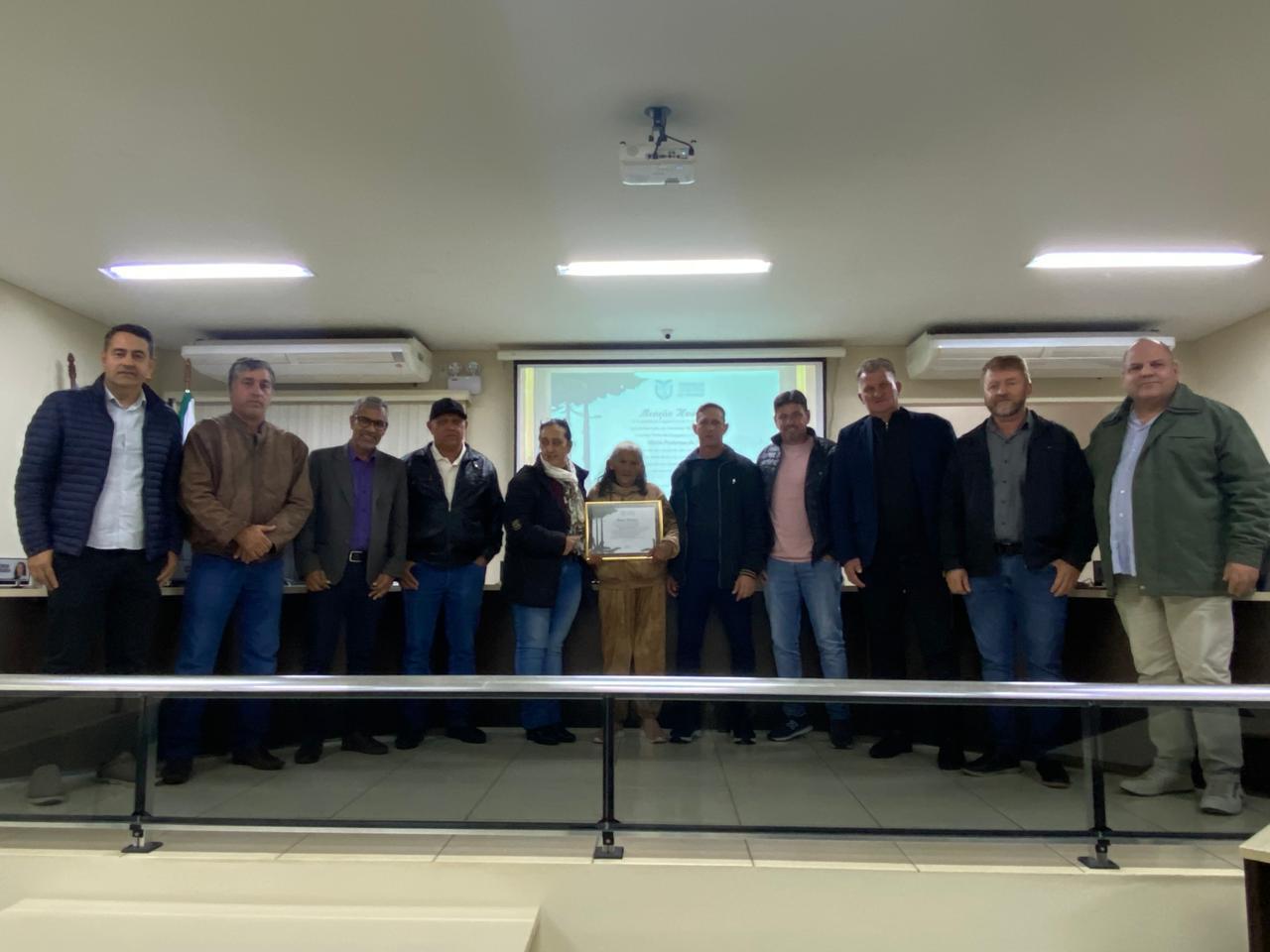 Dona Maria Poderosa da Silva recebe a placa de homenagem durante sessão solene na Câmara Municipal de Jardim Alegre.